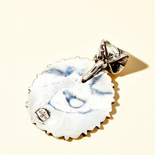 Silver stamp pendant on a beige background