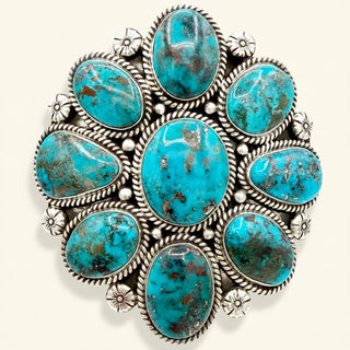 Turquoise stone cuff with silver detailing on a white background