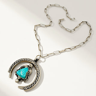 Silver necklace with turquoise stone on a beige background