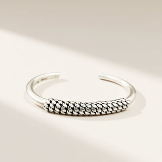 Silver bracelet with textured design on a light beige background
