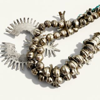 Silver beaded necklace with metal animal figures on a white background