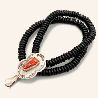 Black beaded necklace with a silver and red stone pendant on a white background