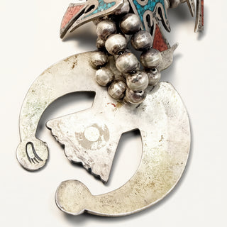 Silver pendant with textured design and beads on a white background