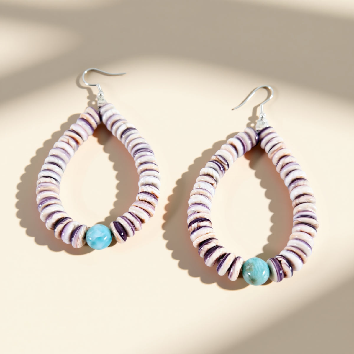 Hoop earrings with multicolored beads on a beige background