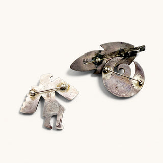 three silver pins on a beige background