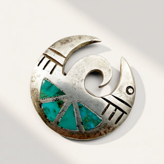 A sterling silver crescent moon pendant with turquoise stone inlay, photographed on a clean white background with soft shadows.