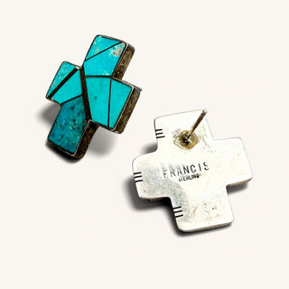 A pair of vintage Southwestern-style cross earrings by Francis,  featuring turquoise inlay on a sterling silver base, shown on a light cream background.
