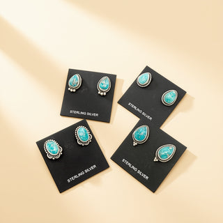 Four pairs of turquoise earrings on black cards with 'Sterling Silver' text on a beige background.