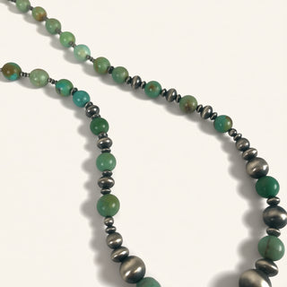 Necklace with green and silver beads on a white background
