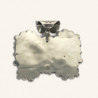 Silver pendant with scalloped edge on a white background